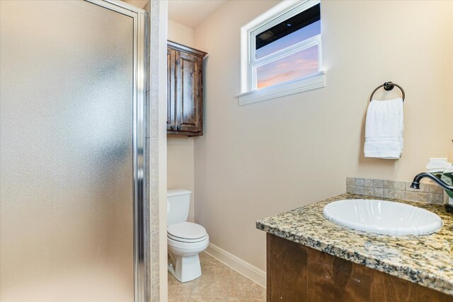 bathroom featuring tile patterned floors, toilet, a stall shower, baseboards, and vanity