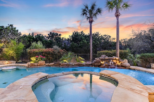 view of swimming pool featuring fence and a pool with connected hot tub