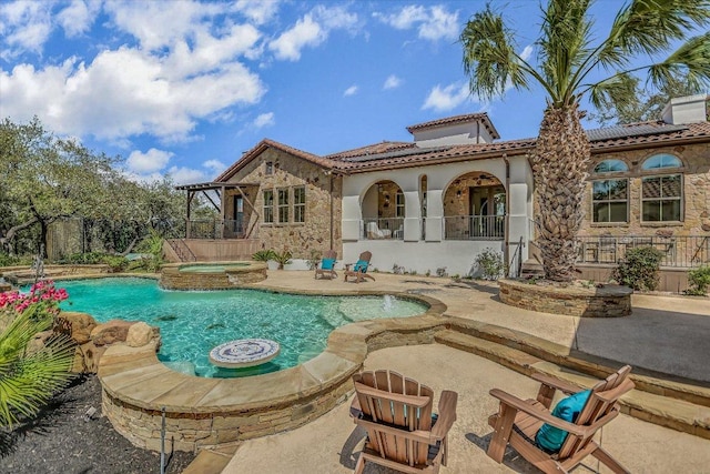 back of property featuring stucco siding, a patio, an outdoor pool, an in ground hot tub, and a tiled roof