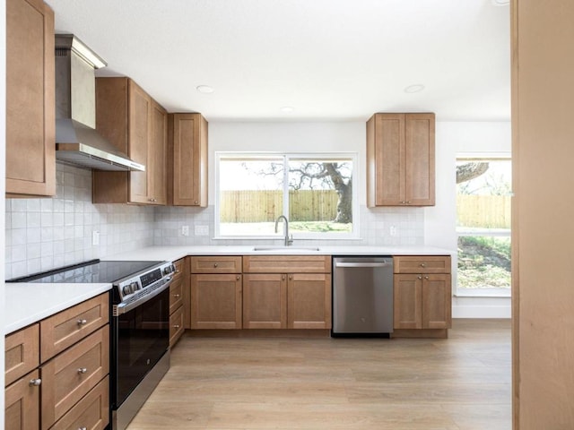 1403 E Applegate Dr, Austin, TX 78753 - kitchen with wall chimney range hood, stainless steel appliances, light wood finished floors, light countertops, and recessed lighting