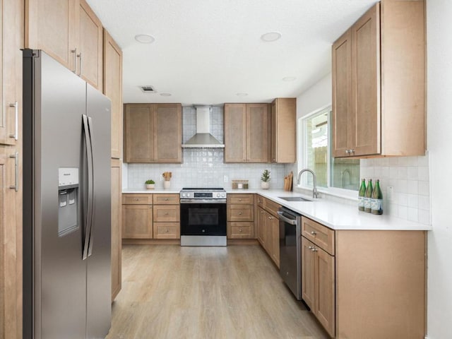 1403 E Applegate Dr, Austin, TX 78753 - kitchen featuring appliances with stainless steel finishes, wall chimney range hood, a sink, light wood finished floors, and decorative backsplash