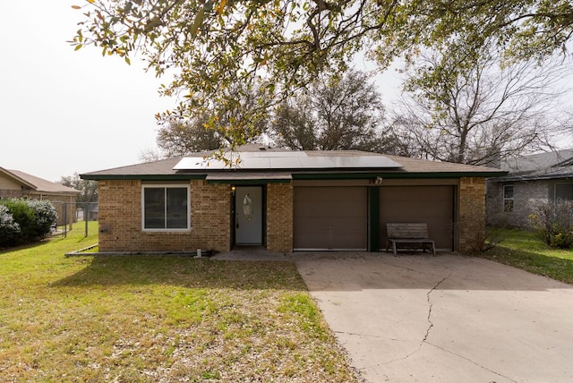 view of front of house featuring a front yard, driveway, solar panels, a garage, and brick siding