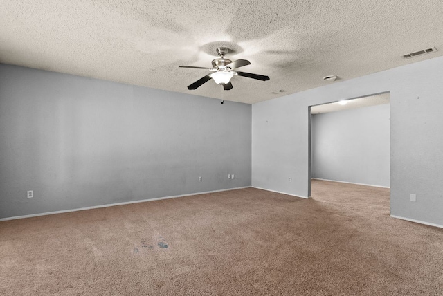 carpeted spare room with visible vents, baseboards, a textured ceiling, and ceiling fan