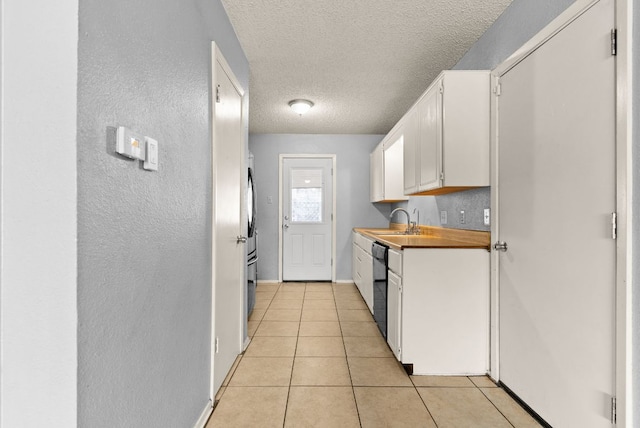 kitchen featuring dishwasher, light tile patterned floors, white cabinets, a textured ceiling, and a sink