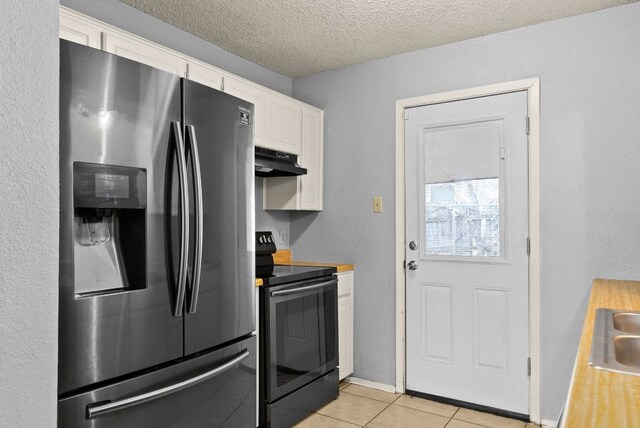 kitchen featuring black range with electric stovetop, under cabinet range hood, stainless steel fridge, white cabinets, and light tile patterned floors