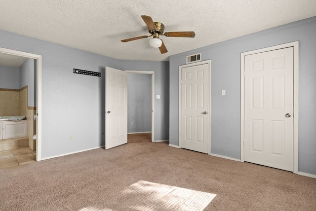 unfurnished bedroom featuring visible vents, a textured ceiling, ensuite bathroom, and carpet