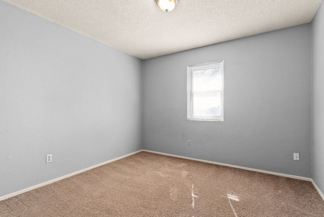 carpeted empty room featuring a textured ceiling and baseboards