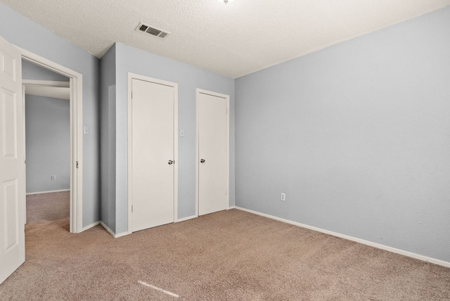 unfurnished bedroom with visible vents, a textured ceiling, baseboards, and carpet floors