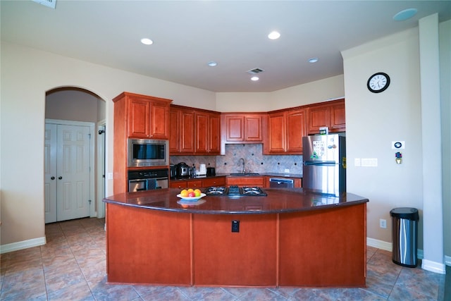 11608 Spicewood Pkwy Unit 38, Austin, TX 78750 - kitchen featuring stainless steel appliances, dark countertops, a center island, tasteful backsplash, and arched walkways