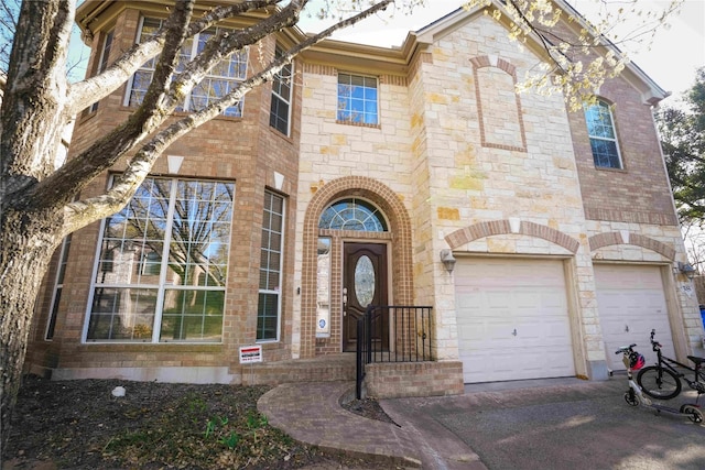 11608 Spicewood Pkwy Unit 38, Austin, TX 78750 - view of exterior entry with an attached garage, stone siding, driveway, and brick siding