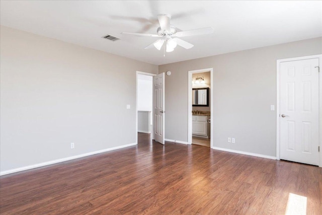 unfurnished bedroom featuring wood finished floors, baseboards, ceiling fan, and ensuite bath