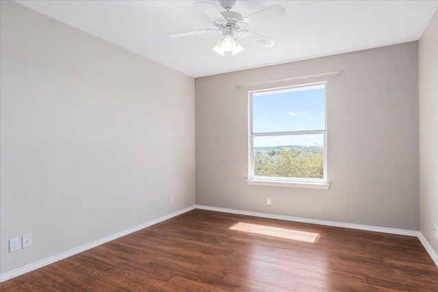 spare room with baseboards, dark wood-style flooring, and a ceiling fan