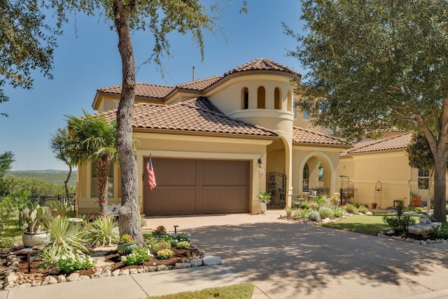 mediterranean / spanish home featuring an attached garage, stucco siding, driveway, and a tile roof