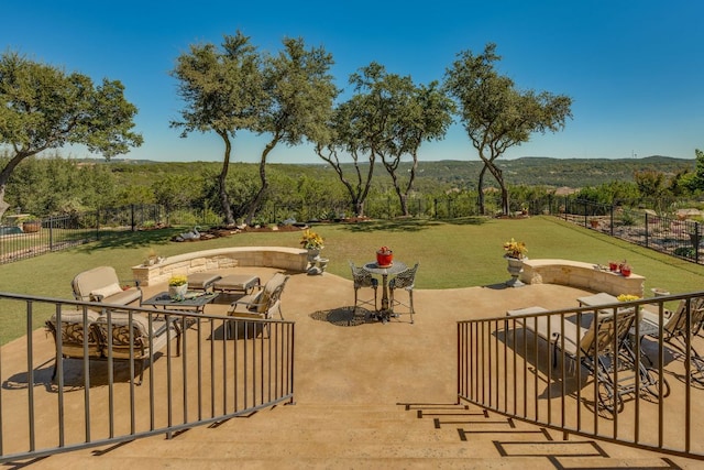 view of home's community with an outdoor living space, a patio, fence, and a forest view