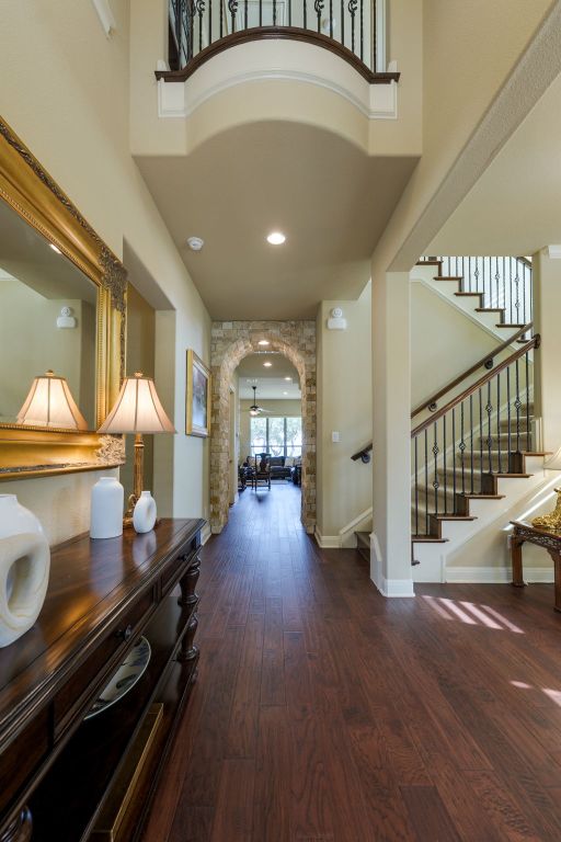 foyer featuring stairs, arched walkways, a high ceiling, and wood finished floors