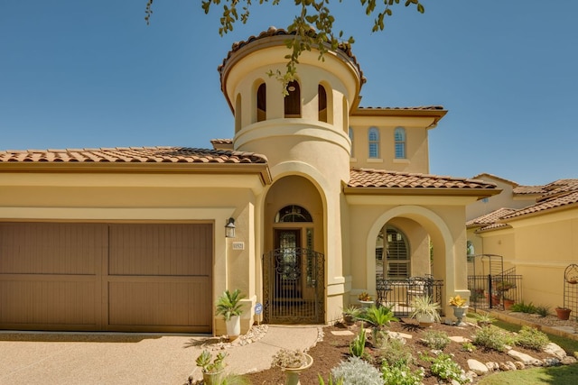 mediterranean / spanish home featuring driveway, a tile roof, fence, an attached garage, and stucco siding