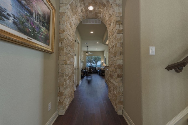 hall featuring arched walkways and dark wood-style floors