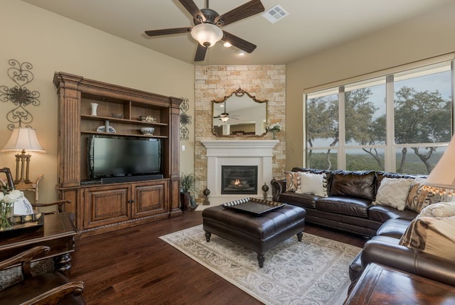living area with a fireplace, a ceiling fan, visible vents, and dark wood-type flooring