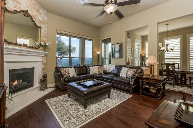 living area with ceiling fan with notable chandelier, wood finished floors, and a fireplace
