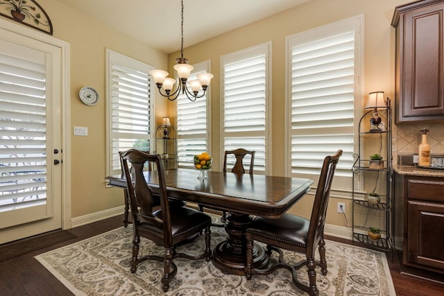 dining room featuring baseboards, a chandelier, plenty of natural light, and dark wood-type flooring