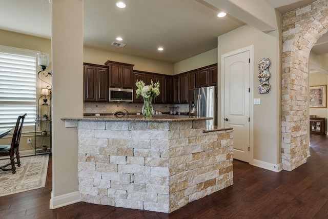 kitchen with dark brown cabinetry, dark wood-style flooring, visible vents, appliances with stainless steel finishes, and arched walkways
