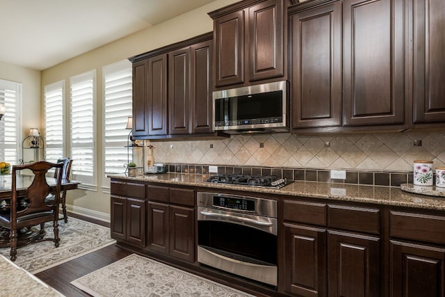 kitchen with appliances with stainless steel finishes, a healthy amount of sunlight, dark brown cabinets, and tasteful backsplash