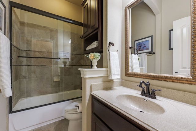 bathroom featuring vanity, enclosed tub / shower combo, tile patterned floors, and toilet