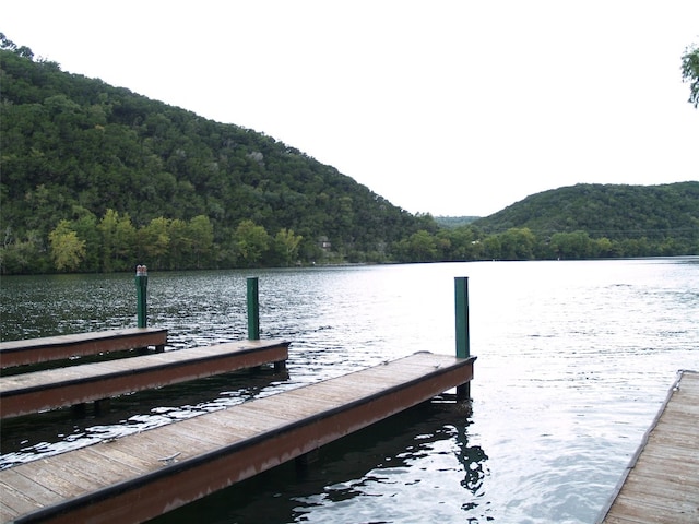 view of dock with a forest view and a water and mountain view