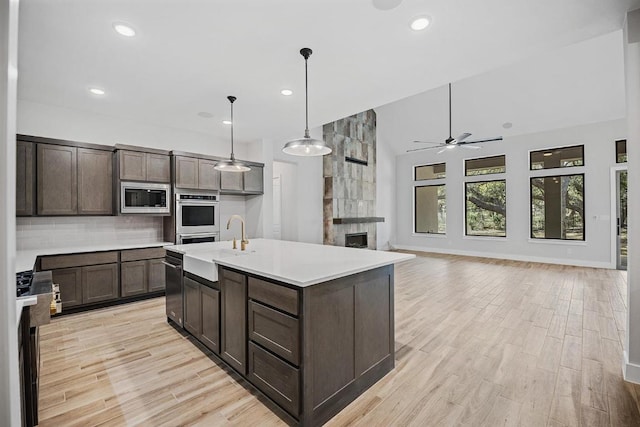 390 Crosswater Ln, Dripping Springs, TX 78620 - kitchen with stainless steel appliances, dark brown cabinets, a ceiling fan, decorative backsplash, and light countertops