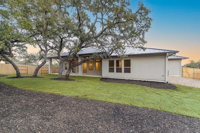 390 Crosswater Ln, Dripping Springs, TX 78620 - back of house at dusk with a standing seam roof, metal roof, and stucco siding
