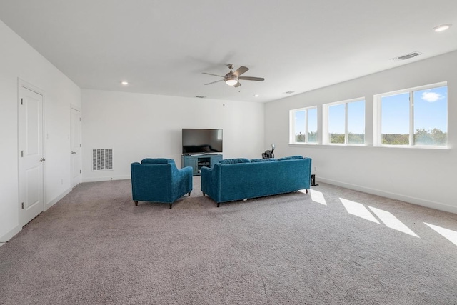 living area featuring carpet flooring, baseboards, visible vents, and ceiling fan