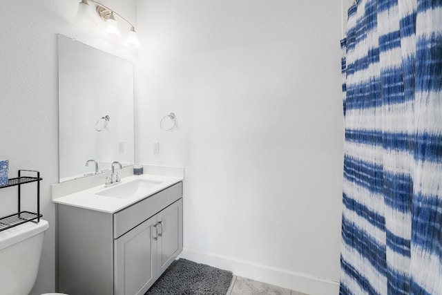 bathroom with toilet, vanity, and baseboards