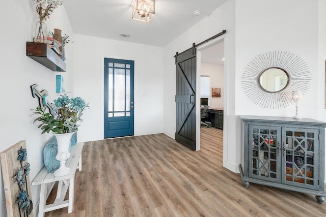 foyer with visible vents, baseboards, a barn door, and wood finished floors