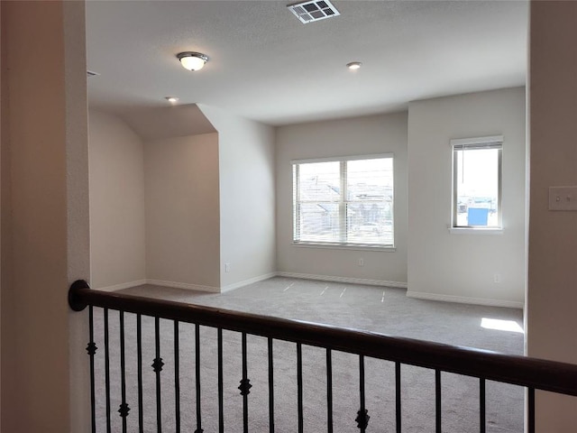 carpeted spare room with visible vents and baseboards