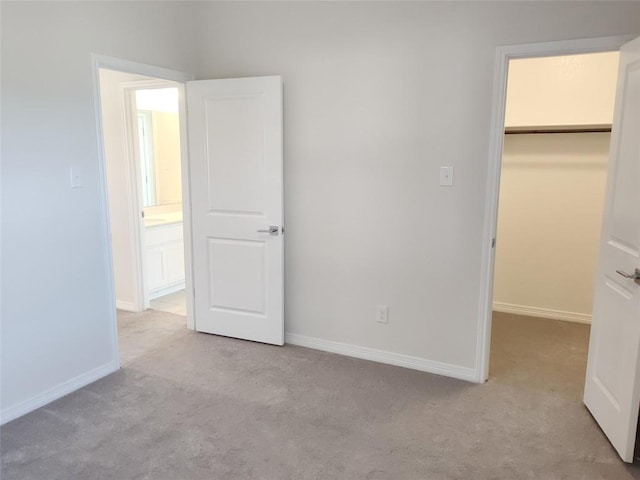 unfurnished bedroom with baseboards, carpet floors, and a spacious closet
