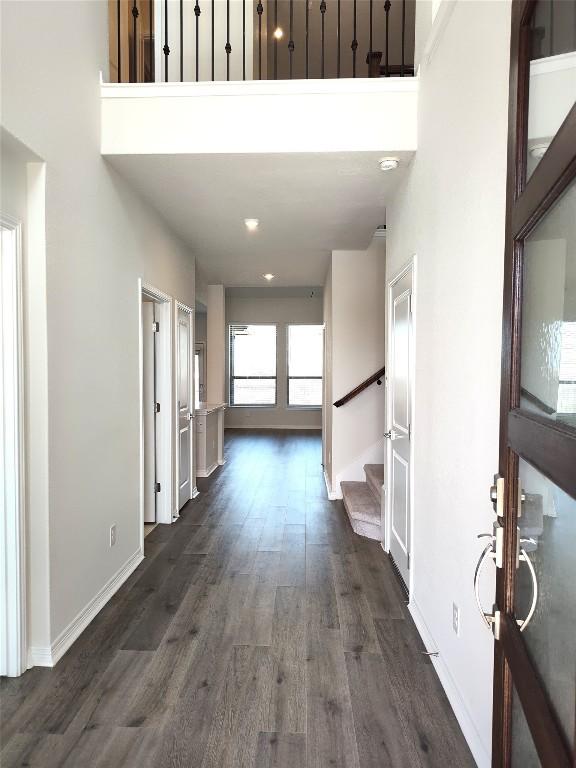 entryway featuring baseboards, a high ceiling, dark wood-style floors, and stairs