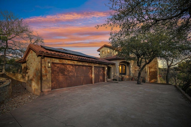 23617 Indian Divide Cv, Spicewood, TX 78669 - mediterranean / spanish home with roof mounted solar panels, a tiled roof, concrete driveway, and a garage