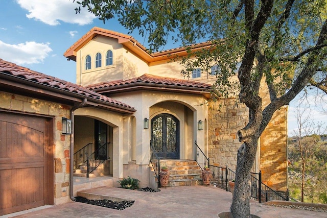 23617 Indian Divide Cv, Spicewood, TX 78669 - mediterranean / spanish-style house featuring french doors, a tiled roof, stone siding, and stucco siding