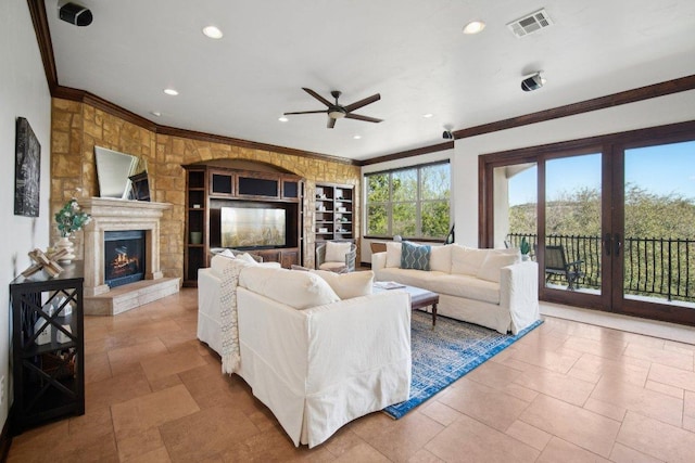 23617 Indian Divide Cv, Spicewood, TX 78669 - living room with a ceiling fan, a lit fireplace, crown molding, recessed lighting, and stone tile flooring