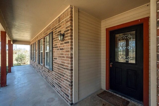 property entrance featuring brick siding and covered porch