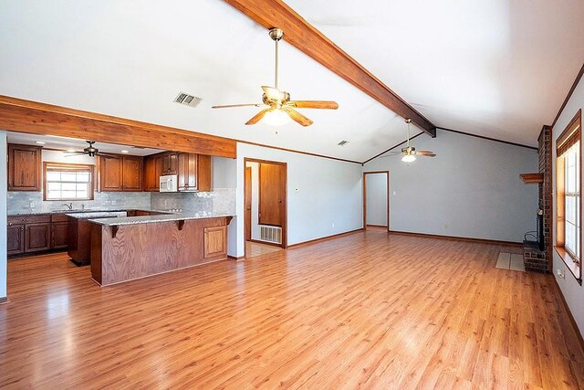 kitchen with a peninsula, white microwave, visible vents, and ceiling fan