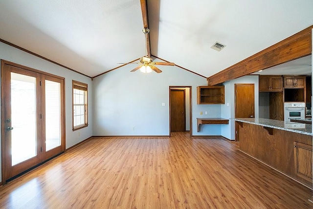 unfurnished living room featuring visible vents, a ceiling fan, lofted ceiling with beams, light wood-style floors, and baseboards