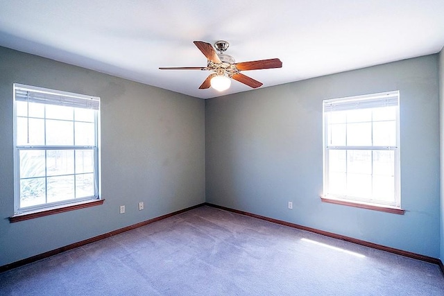 carpeted spare room with a ceiling fan, baseboards, and a wealth of natural light