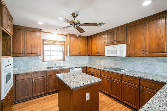 kitchen with white appliances, light wood-type flooring, ceiling fan, and a sink