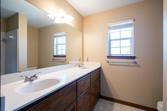 full bath with a sink, baseboards, toilet, and double vanity