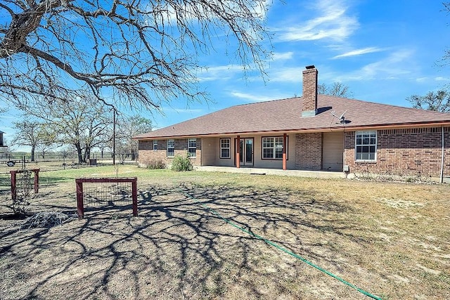 rear view of house featuring a lawn, brick siding, and a chimney