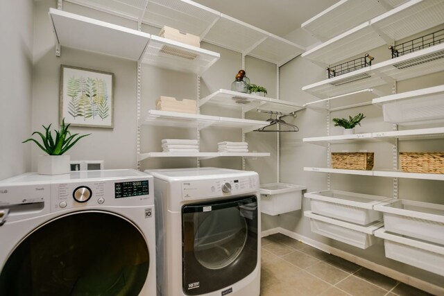 washroom with laundry area, washer and clothes dryer, baseboards, and tile patterned floors