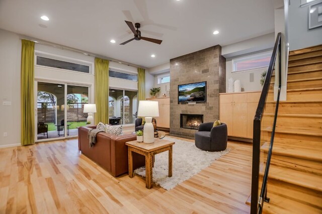 living room featuring a large fireplace, a ceiling fan, recessed lighting, light wood-type flooring, and stairway