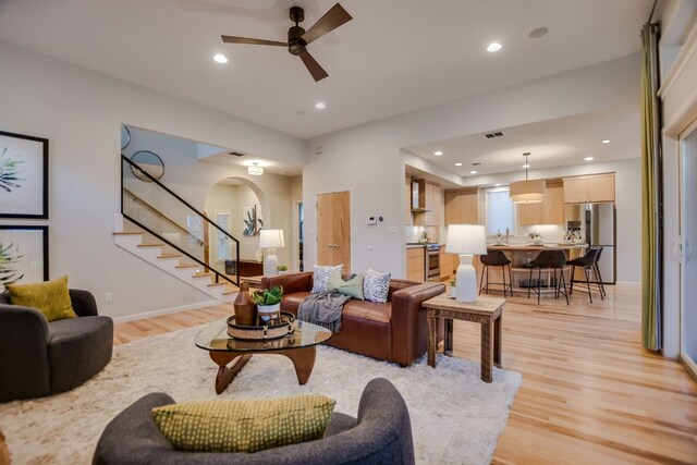 living area featuring light wood-type flooring, recessed lighting, ceiling fan, and stairway