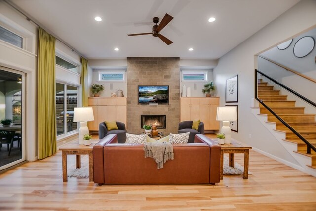 living room featuring a large fireplace, ceiling fan, recessed lighting, and wood finished floors